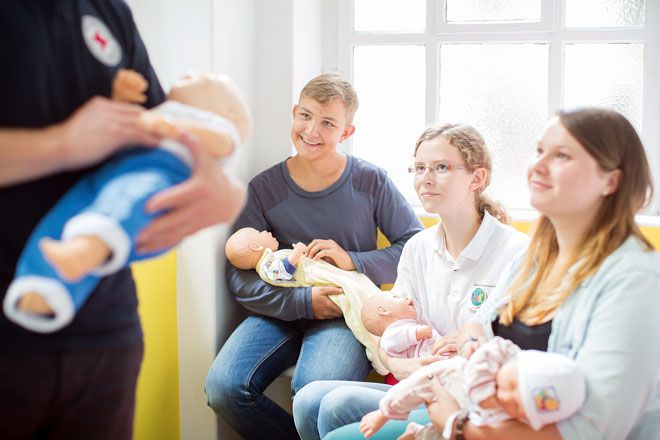 Foto: Ein Kleinstkind blickt mit strahlendem Lachen über die Schulter seiner Mutter.